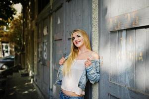 Blonde girl wear on jeans jacket posed at street. photo