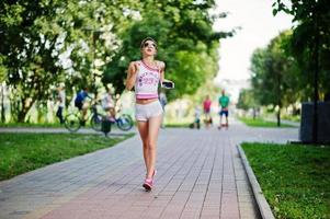 ropa de niña deportiva en pantalones cortos blancos y camisa corriendo en el parque. foto