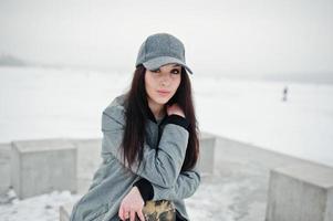Stylish brunette girl in gray cap, casual street style on winter day. photo