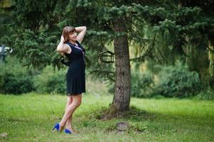 retrato de una hermosa chica vestida de negro en una despedida de soltera, posada en el parque. foto