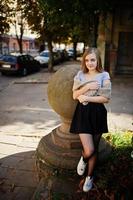 Young blonde girl in black skirt with scarf posed at street of city. photo