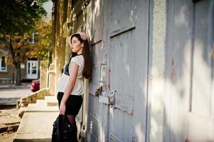 Stylish brunette girl wear on leather jacket and shorts posing at street. photo