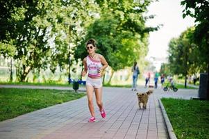 ropa de niña deportiva en pantalones cortos blancos y camisa corriendo en el parque. foto