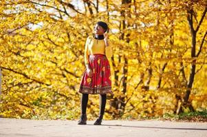 African american girl at yellow and red dress at golden autumn fall park. photo