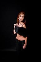 Fashion model red haired girl with originally make up like leopard predator isolated on black. Studio portrait. photo