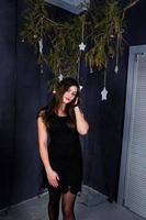 Cute girl wear on black dress against christmas decoration. photo