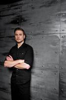 Studio portrait of stylish man wear on black shirt against steel wall. photo