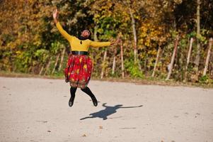 African american girl at yellow and red dress at golden autumn fall park. photo