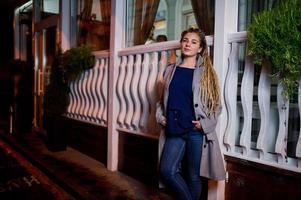 chica con rastas caminando por la calle de noche de la ciudad. foto