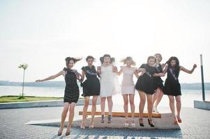 grupo de 7 chicas vestidas de negro y 2 novias saltando en la despedida de soltera. foto