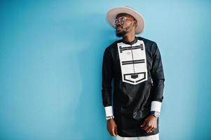 retrato de un elegante hombre afroamericano negro con sombrero y gafas sobre fondo azul. foto