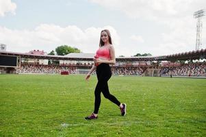 Fitness sporty girl in sportswear at stadium outdoor sports. Happy sexy woman with sport bottle mockup. photo