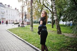 elegante chica rubia vestida con chaqueta de cuero negro posando en las calles de la ciudad. foto