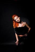 Fashion model red haired girl with originally make up like leopard predator isolated on black. Studio portrait. photo