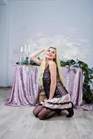 Elegante blonde girl wear on black dress sitting against table with christmas decoration. photo