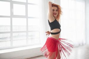 Stripes spinning around. Attractive woman in red skirt posing in the spacey room near the window photo