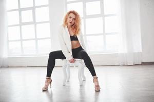 White chair. Attractive redhead woman posing in the spacey room near the window photo