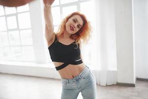 Positive dancer. Attractive redhead woman posing in the spacey room near the window photo