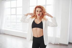 Gorgeous person. Attractive redhead woman posing in the spacey room near the window photo