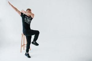 Some kind of modern meme gesture. Positive man in casual clothes have fun in the studio against white wall photo