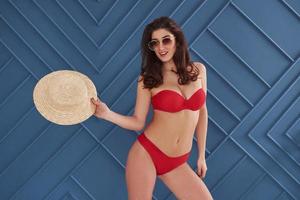 Taking off the hat. Stylish beautiful young girl in bikini stands and posing in the studio photo