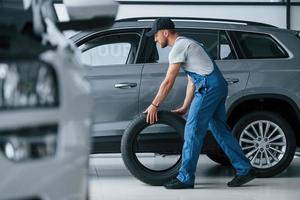 New one. Mechanic holding a tire at the repair garage. Replacement of winter and summer tires photo