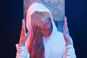 Holding glass. Studio shot in dark studio with neon light. Portrait of young girl photo