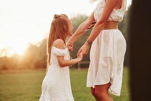 In golden colored watch. Mother and daughter enjoying weekend together by walking outdoors in the field. Beautiful nature photo