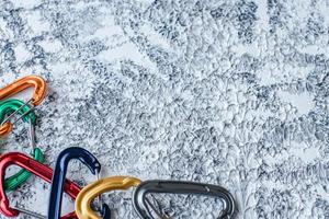 On the edge of picture. Isolated photo of climbing equipment. Part of carabiner lying on the white and grey colored surface