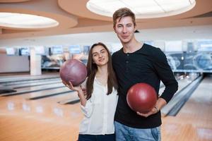 Big hall. Young cheerful friends have fun in bowling club at their weekends photo