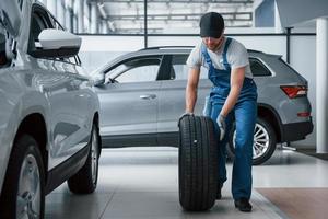 Almost done. Mechanic holding a tire at the repair garage. Replacement of winter and summer tires photo