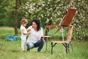 Little helper. Teaching granddaughter how to paint. In the natural parkland photo