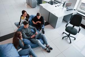 Man with short hair is typing on keyboard. Group of young people in casual clothes working in the modern office photo