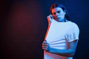 Posing for the camera. Studio shot in dark studio with neon light. Portrait of serious man photo