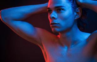 Clean skin. Studio shot in dark studio with neon light. Portrait of serious man photo