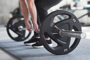 Before pushing it up. Cropped photo of woman doing squatting with barbell in the gym