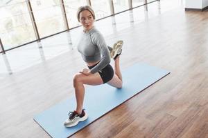 Near the big window. Sportive young woman have fitness day in the gym at morning time photo