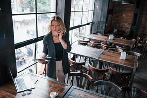 leyendo el documento. mujer de negocios con cabello rubio rizado en el interior de la cafetería durante el día foto