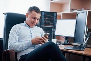 Reading some good news. Man working online in the office with multiple computer screens in index charts photo