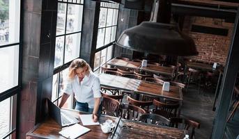 psicólogo ocupado. mujer de negocios con cabello rubio rizado en el interior de la cafetería durante el día foto