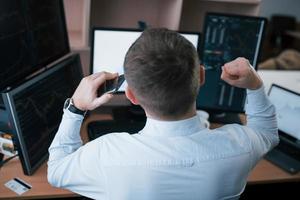 Successful young businessman. Man working online in the office with multiple computer screens in index charts photo