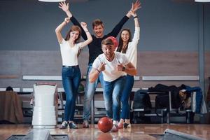 This is win. Young cheerful friends have fun in bowling club at their weekends photo