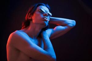Showing body. Studio shot in dark studio with neon light. Portrait of serious man photo