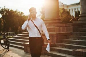 Going forward. Businessman in formal clothes with black bicycle is in the city photo