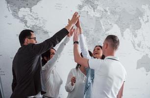 Celebrating success. Team of freelancers standing against wall with map of the world on it photo