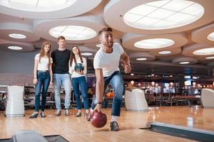 Going to win. Young cheerful friends have fun in bowling club at their weekends photo