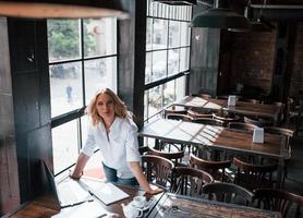 buen humor. mujer de negocios con cabello rubio rizado en el interior de la cafetería durante el día foto