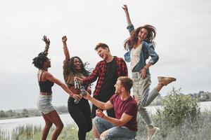 Cheers to all. Group of people have picnic on the beach. Friends have fun at weekend time photo