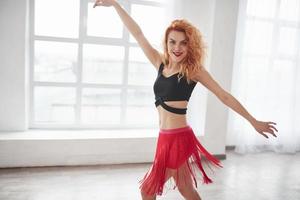 Graceful girl. Attractive woman in red skirt posing in the spacey room near the window photo