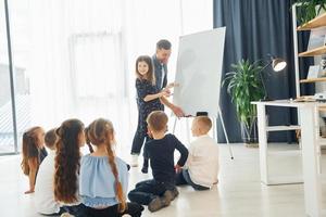 Girl writing on the board. Group of children students in class at school with teacher photo